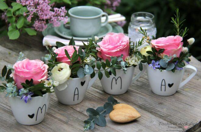 vier Kaffeetassen mit Schriftzug Mama gefüllt mit Rosen und Blüten